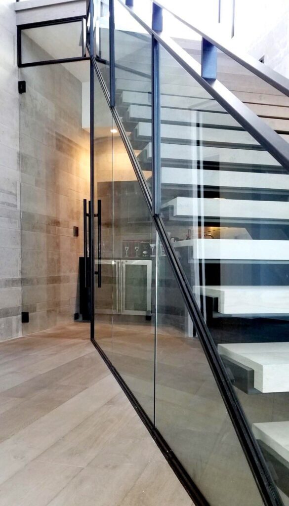 A glass stairwell with a bar behind